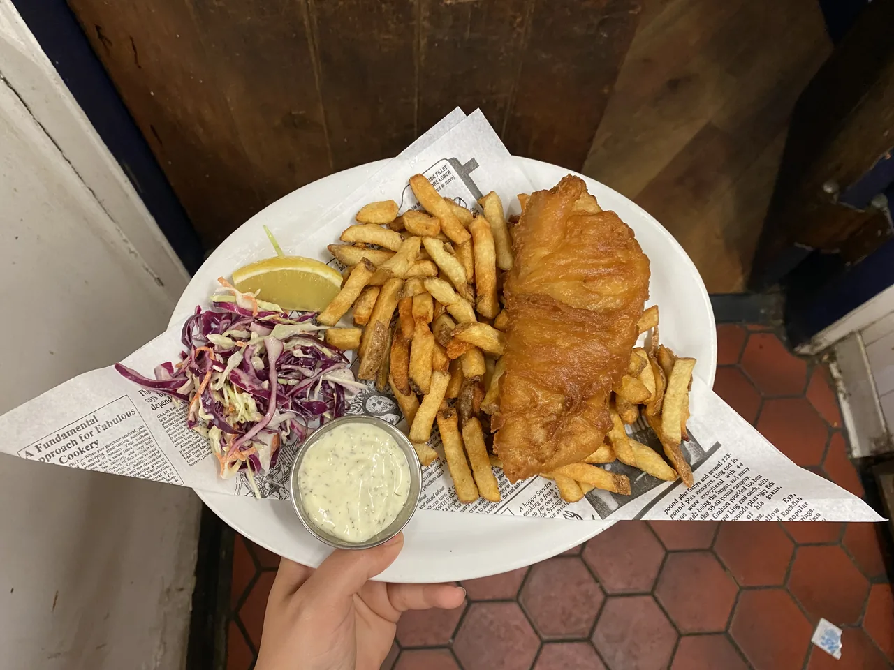 A plate of fish and chips held up in the pub