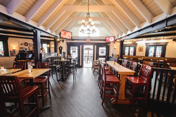 The main room under its vaulted white ceiling and iron chandelier, a door open to the deck