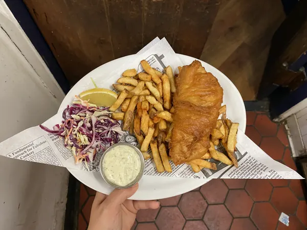 A plate of fish and chips held up in the pub