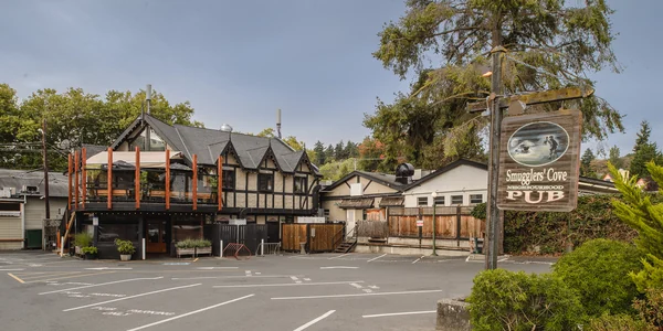 The Smugglers' Cove pub sign beside the parking lot, with the Tudor building behind