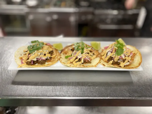Three tacos lined up on the pass