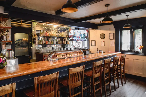 The long wooden bar with its chrome tap tower, bottles lit up behind