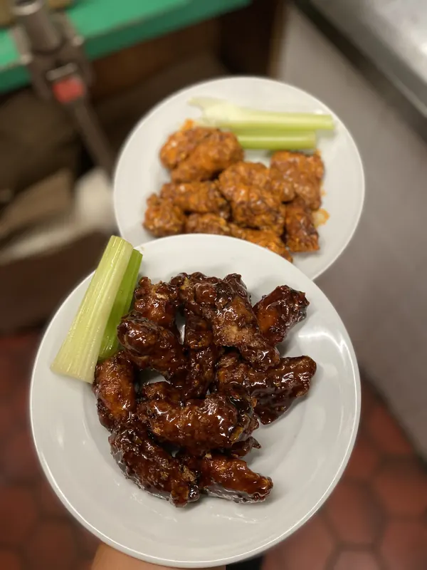 Two plates of wings in different sauces